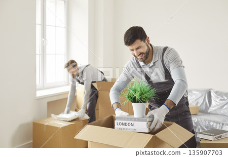 Smiling movers packing household items into boxes during efficient relocation Smiling movers packing household items into boxes during efficient relocation 135907703