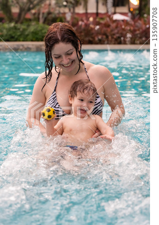 Caucasian woman holds her son while swimming in a pool on vacation. Mom teaches little boy to swim. Caucasian woman holds her son while swimming in a pool on vacation. Mom teaches little boy to swim. 135907708