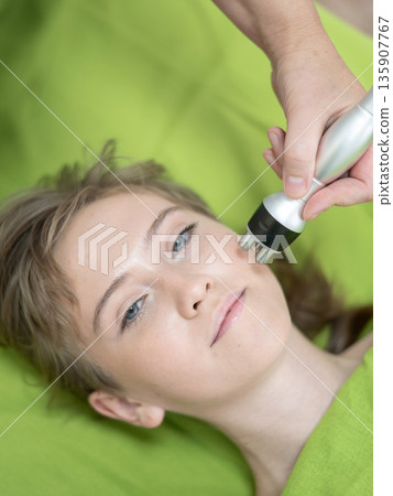 Top view of Caucasian woman undergoing radio wave RF lifting procedure in beauty salon. Top view of Caucasian woman undergoing radio wave RF lifting procedure in beauty salon. 135907767