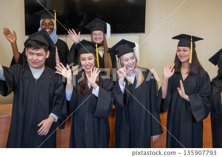 Young multinational people in graduation gowns stand at the lectern. Young multinational people in graduation gowns stand at the lectern. 135907793