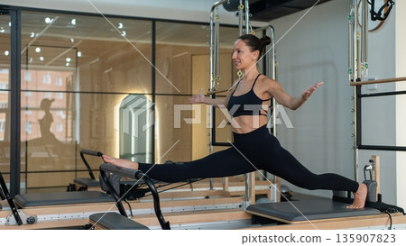 Caucasian woman doing splits on reformer.  135907823