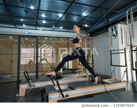 Caucasian woman doing splits on reformer.  135907824