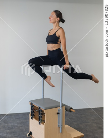Caucasian woman doing Pilates on classic chair. Caucasian woman doing Pilates on classic chair. 135907829