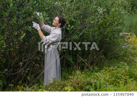 Young Caucasian woman trimming bushes. Young Caucasian woman trimming bushes. 135907840