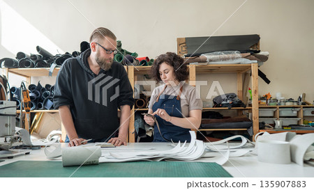 A man and a woman work as tanners in a workshop.  135907883