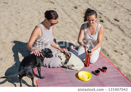 Two Caucasian women on a picnic on the beach.  135907942