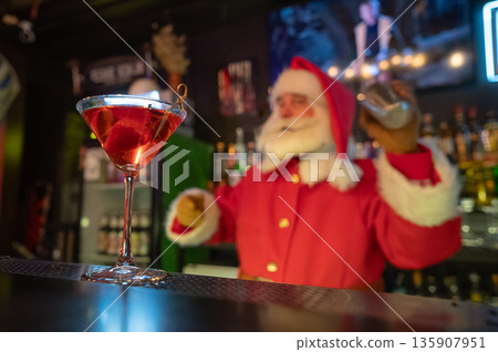 Santa Claus works at the bar making cocktails in a shaker.  135907951