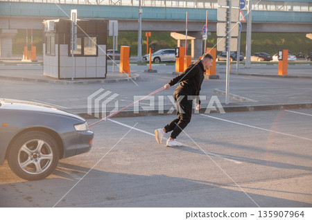 Caucasian man pulling a car with a rope.  135907964