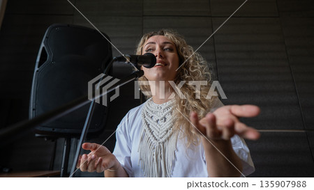 Caucasian woman singing into microphone in music studio.  135907988
