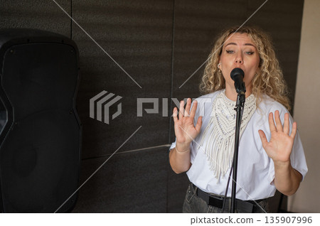 Caucasian woman singing into microphone in music studio. Caucasian woman singing into microphone in music studio. 135907996