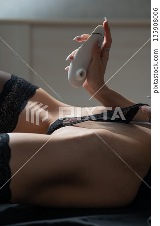 A woman holds a vacuum vibrator near her panties.. A woman holds a vacuum vibrator near her panties.. 135908006