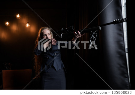 A Caucasian woman in a business suit holds a rifle with a scope.  135908023