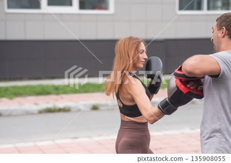 Man and woman sparring outdoors. Boxing lesson. Man and woman sparring outdoors. Boxing lesson. 135908055