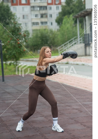 A Caucasian woman practices boxing outdoors. A Caucasian woman practices boxing outdoors. 135908056