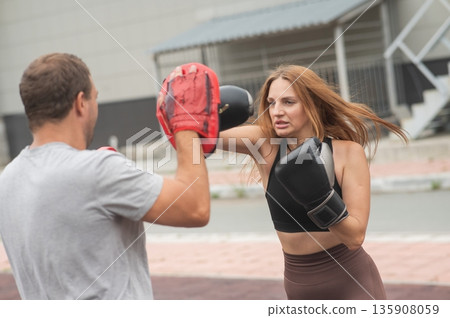 Man and woman sparring outdoors. Boxing lesson. Man and woman sparring outdoors. Boxing lesson. 135908059