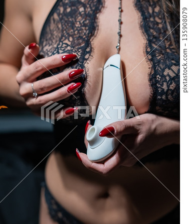Woman in lace lingerie holding white clitoral vacuum stimulator.  135908079