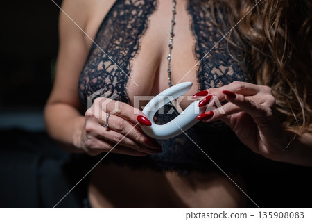 A woman in black lingerie holds a curved vibrator.  135908083