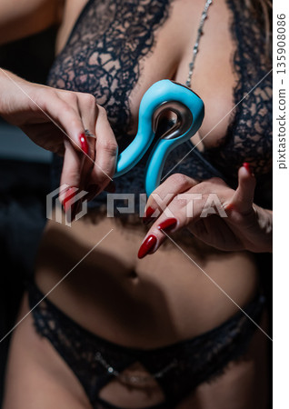 A woman in black lingerie holds a curved vibrator.  135908086