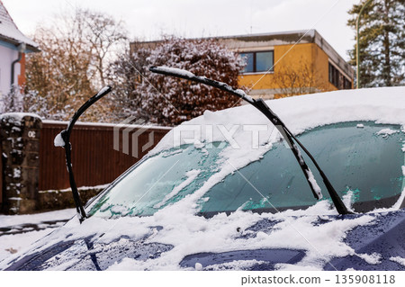 Snow covered car windshield with raised wiper blades, parked in residential street Snow covered car windshield with raised wiper blades, parked in residential street 135908118