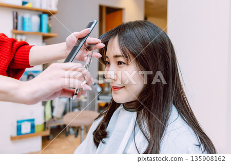 Female hairdresser cutting hair at beauty salon 135908162