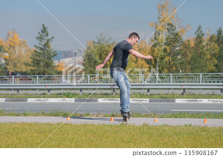 A Caucasian man rollerblades around the slalom course. A Caucasian man rollerblades around the slalom course. 135908167