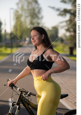 Curvy Caucasian Woman Riding Bicycle in Park. Curvy Caucasian Woman Riding Bicycle in Park. 135908219