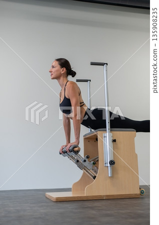 Caucasian woman doing Pilates on classic chair. 135908235