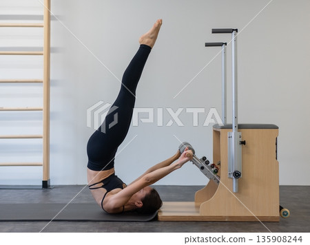 Caucasian woman doing Pilates on classic chair. Caucasian woman doing Pilates on classic chair. 135908244