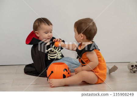 Cute kids celebrate halloween on white background. Two little boys in dracula costume and pumpkin.  135908249