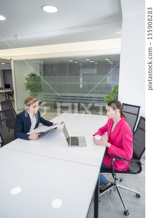 Man and woman talking while sitting at desk in office. Man and woman talking while sitting at desk in office. 135908283