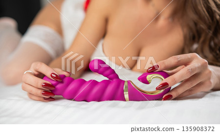 Caucasian woman in santa claus costume and stockings lies on bed with sex toy.  135908372