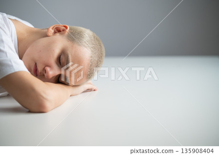 Sad woman sitting with her head on the table on a white background. 135908404