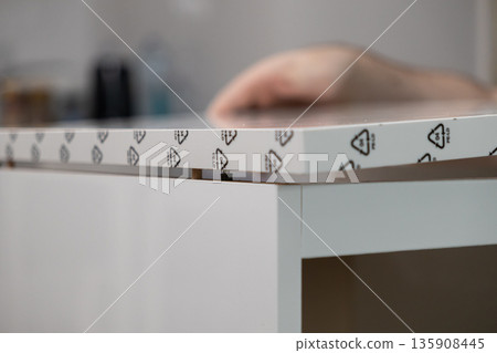 Assembling white furniture panel reveals 04 PE-LD recycling symbol, dowels, and cam lock, emphasizing responsible material choice for sustainable home improvement 135908445