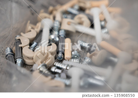 A diverse collection of furniture assembly hardware, including various screws, dowels, and cam locks, crucial for successful do-it-yourself home construction and repair projects A diverse collection of furniture assembly hardware, including various screws, dowels, and cam locks, crucial for successful do-it-yourself home construction and repair projects 135908550