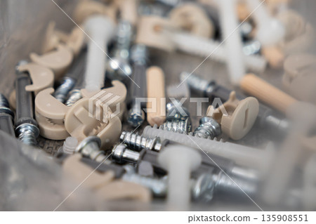 Various furniture assembly hardware components including screws, wooden dowels, and cam locks, essential for DIY home projects and product construction 135908551