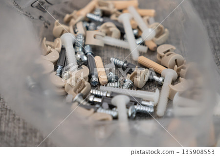 Assorted furniture assembly hardware, featuring various screws, dowels, and cam locks, crucial for home improvement, DIY furniture construction projects Assorted furniture assembly hardware, featuring various screws, dowels, and cam locks, crucial for home improvement, DIY furniture construction projects 135908553