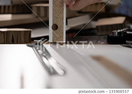 Hand assembling particle board furniture components with dowels, showcasing DIY construction for home improvement, demonstrating practical skill Hand assembling particle board furniture components with dowels, showcasing DIY construction for home improvement, demonstrating practical skill 135908557