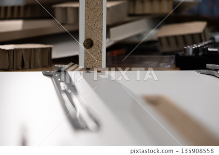 Assembling a modern flat-pack furniture panel, demonstrating the efficient use of a wooden dowel and metal cam lock system for quick and simple DIY home improvement 135908558