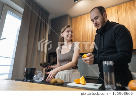 A Caucasian couple prepares freshly squeezed juice. A Caucasian couple prepares freshly squeezed juice. 135908666