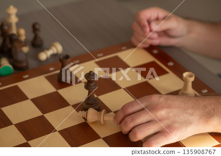 Close up of hands of middle aged caucasian man playing chess.  135908767