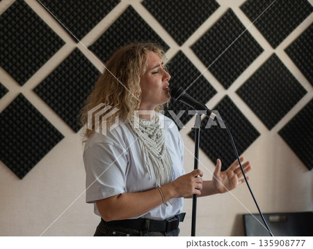 Caucasian woman singing into microphone in music studio. Caucasian woman singing into microphone in music studio. 135908777