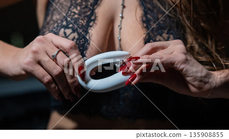 A woman in black lingerie holds a curved vibrator.  135908855