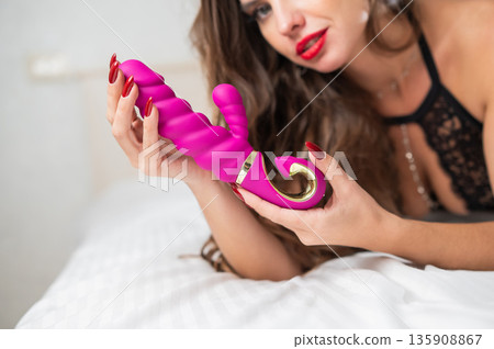 Woman in lace lingerie holds a dildo.  135908867