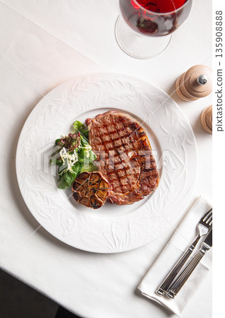 Grilled beef steak with roasted garlic and greens 135908888