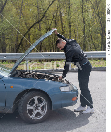 Caucasian man looking under the hood of his car. Caucasian man looking under the hood of his car. 135908898