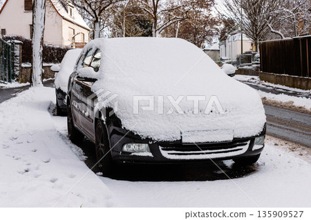 Winter residential street scene with a parked car covered in snow beside a cleared sidewalk and snowbanks. Winter residential street scene with a parked car covered in snow beside a cleared sidewalk and snowbanks. 135909527