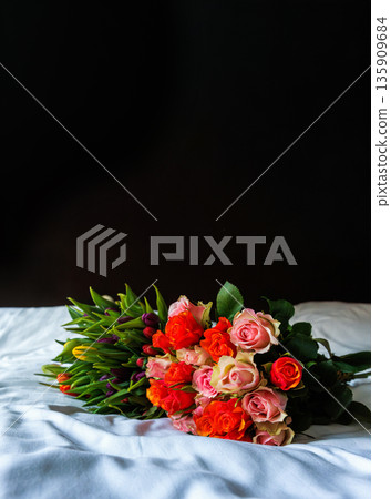 Bouquet of roses and tulips on bed with black copy space background 135909684