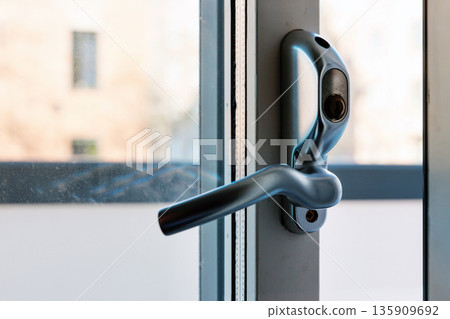 Close up of open window handle on modern frame with blurred city view Close up of open window handle on modern frame with blurred city view 135909692