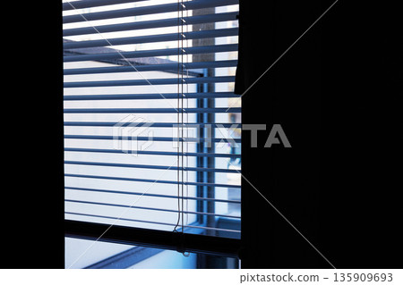 Interior view of horizontal window blinds with soft daylight and shadows, and a large dark area providing copy space. Interior view of horizontal window blinds with soft daylight and shadows, and a large dark area providing copy space. 135909693