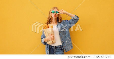 Happy cheerful smiling young woman holding grocery shopping paper bag with white bread baguette 135909740